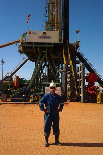 man in protective gear standing in front of large drilling machinery