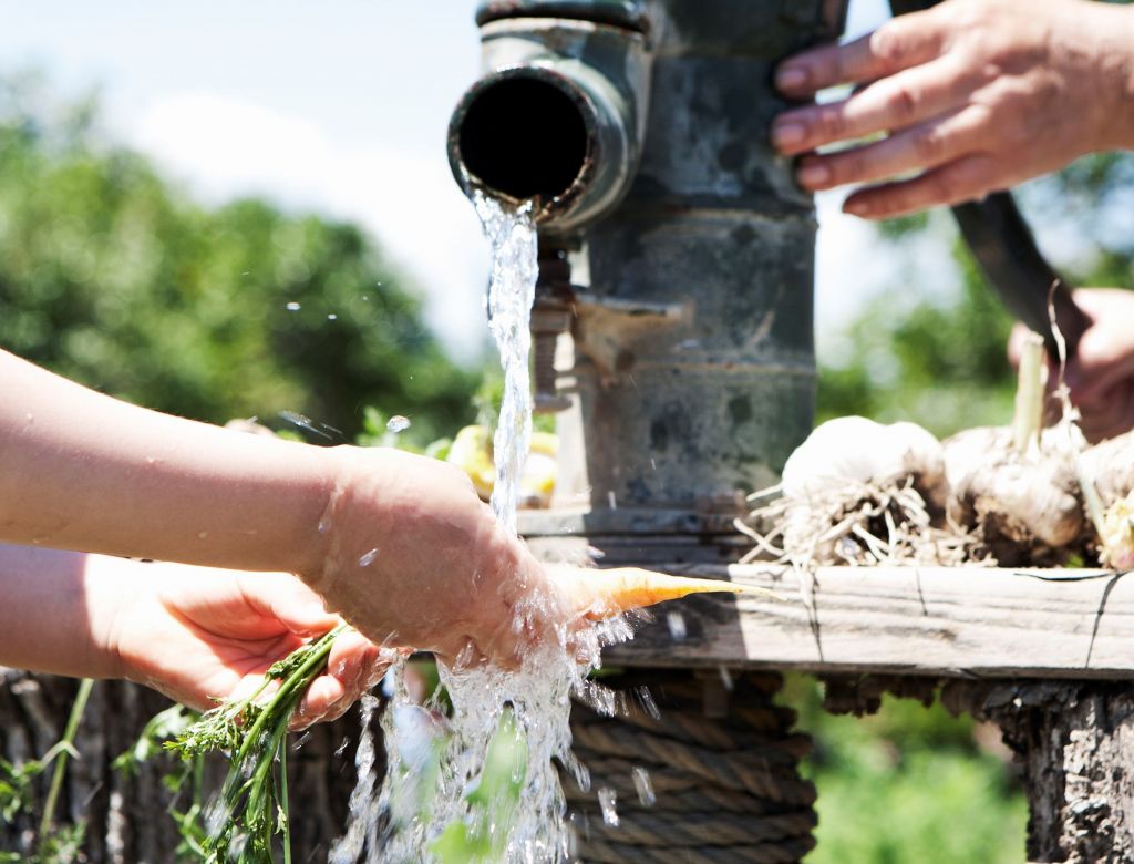 A person washing vegetables with groundwater from a well